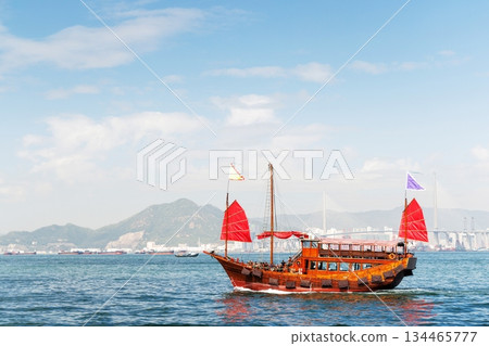 Traditional wooden junk boat with red sails against Hong Kong sk 134465777