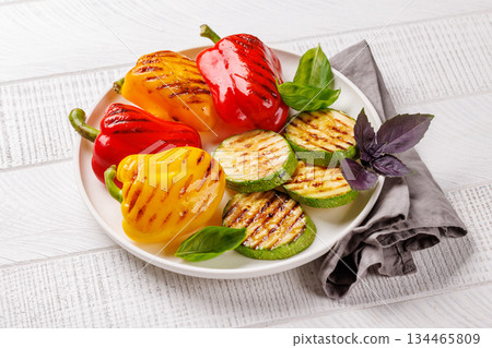 Assorted grilled vegetables including bell peppers, zucchini, eggplant, and fresh herbs 134465809