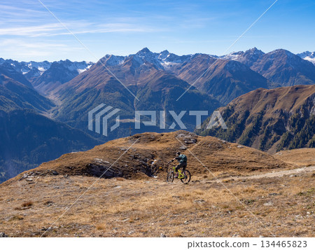 Scuol, Switzerland - October 11th 2025: A female cyclist riding her bike in motta-naluns resort with a fantastic view. 134465823