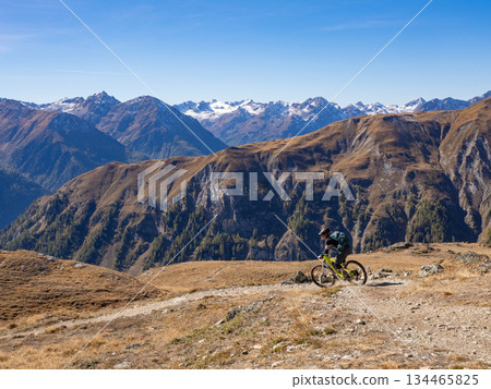 Scuol, Switzerland - October 11th 2025: A female cyclist riding her bike in motta-naluns resort with a fantastic view. Scuol, Switzerland - October 11th 2025: A female cyclist riding her bike in motta-naluns resort with a fantastic view. 134465825