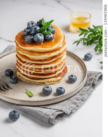 Pancakes with fresh blueberries on a gray plate on a marble background with honey and fresh berries. 134465866