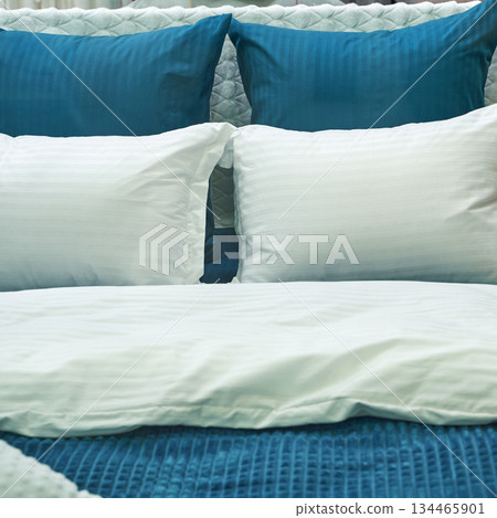 Luxurious bedding arrangement with white pillows and blue quilt in a cozy Luxurious bedding arrangement with white pillows and blue quilt in a cozy 134465901