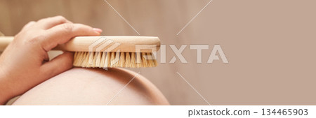 Pregnant female body brushing belly with natural bristle brush for skin care 134465903