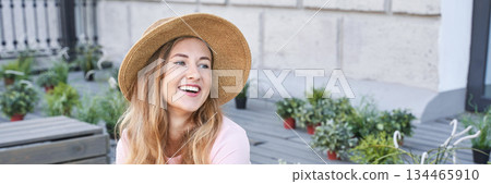Smiling young caucasian female in straw hat enjoying outdoor garden setting Smiling young caucasian female in straw hat enjoying outdoor garden setting 134465910