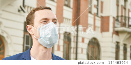 Caucasian male adult wearing face mask outdoors in urban setting 134465924