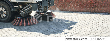 Street sweeper machine with rotating brushes cleaning urban pavement Street sweeper machine with rotating brushes cleaning urban pavement 134465952