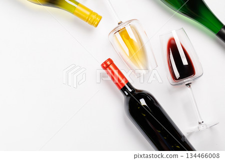 Wine glasses with red and white wine and bottles lying on white background 134466008