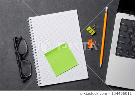 Notepad, office supplies and laptop on black leather workspace, top view with copy space Notepad, office supplies and laptop on black leather workspace, top view with copy space 134466011