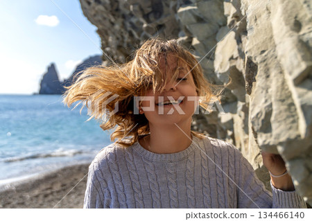 Girl Beach Windswept Hair Azores Islands Coastal Scene: Joyful Child near Ocean Rocks, Sunny Day. Girl Beach Windswept Hair Azores Islands Coastal Scene: Joyful Child near Ocean Rocks, Sunny Day. 134466140