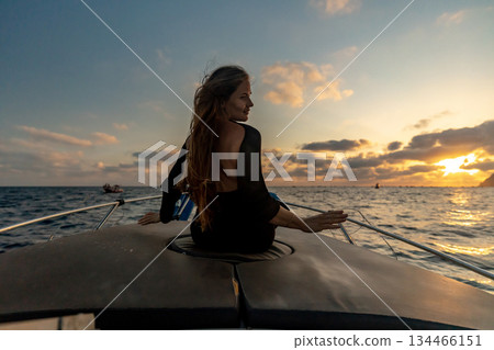 Woman, boat, sunset. Beautiful woman sitting on luxurious boat enjoying tranquil evening at sea during golden hour. Woman, boat, sunset. Beautiful woman sitting on luxurious boat enjoying tranquil evening at sea during golden hour. 134466151