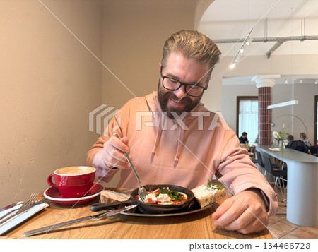 Man dining alone in cafe with breakfast. Morning calm, slow living and appreciation of simple comfort through food and space. Man dining alone in cafe with breakfast. Morning calm, slow living and appreciation of simple comfort through food and space. 134466728