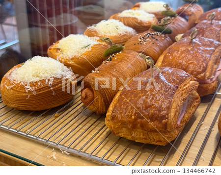 Savory croissants and pastries in bakery display. Texture, flavor, and artisanal baking in modern cafe presentation. Savory croissants and pastries in bakery display. Texture, flavor, and artisanal baking in modern cafe presentation. 134466742