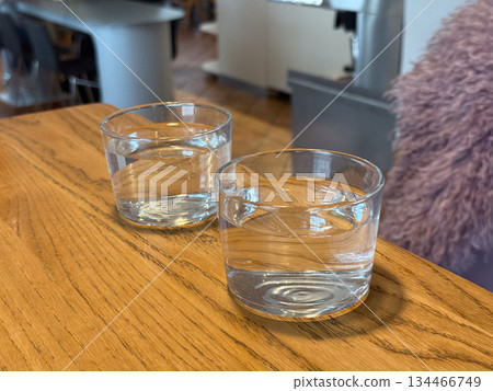 Two glasses of water on wooden cafe table. Simplicity, hydration, and calm atmosphere in social dining environment. 134466749