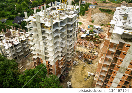 Aerial view of tower lifting crane and concrete frame of tall apartment residential buildings under construction in a city. Urban development and real estate growth concept. 134467194