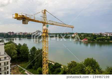 Aerial view of tower lifting crane and concrete frame of tall apartment residential building under construction in a city. Urban development and real estate growth concept. 134467199