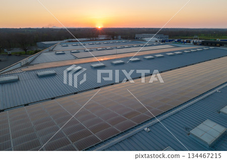 Aerial view of solar power plant with blue photovoltaic panels mounted on industrial building roof for producing green ecological electricity. Production of sustainable energy concept Aerial view of solar power plant with blue photovoltaic panels mounted on industrial building roof for producing green ecological electricity. Production of sustainable energy concept 134467215