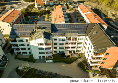 Aerial view of solar photovoltaic panels on a roof top of residential building block for producing clean electric energy. Autonomous housing concept. Aerial view of solar photovoltaic panels on a roof top of residential building block for producing clean electric energy. Autonomous housing concept. 134467219