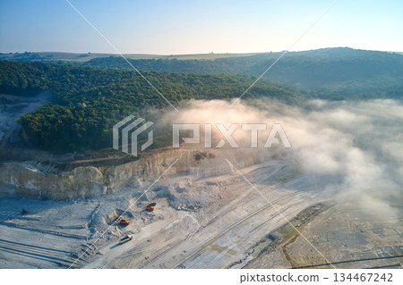 Aerial view of open pit mining of limestone materials for construction industry with excavators and dump trucks. 134467242