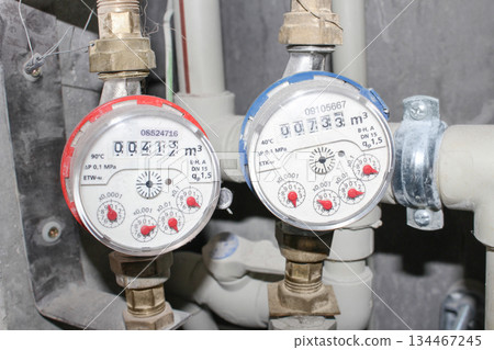 Water meters and plastic pipes installed in an apartment utility room, showing household water consumption Water meters and plastic pipes installed in an apartment utility room, showing household water consumption 134467245