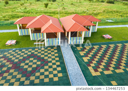 Aerial view of new alcove in kindergarten play yard with red tiled roof for outdoor children activities. 134467253