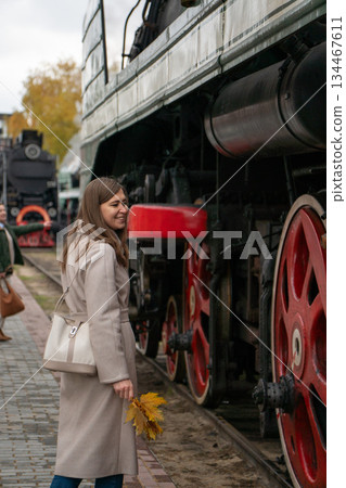 Woman stands beside preserved Soviet-era steam locomotive, looking at large red driving wheels at the Povorotny Krug railway museum Woman stands beside preserved Soviet-era steam locomotive, looking at large red driving wheels at the Povorotny Krug railway museum 134467611