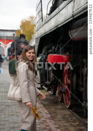 Woman stands beside preserved Soviet-era steam locomotive, looking at large red driving wheels at the Povorotny Krug railway museum Woman stands beside preserved Soviet-era steam locomotive, looking at large red driving wheels at the Povorotny Krug railway museum 134467612