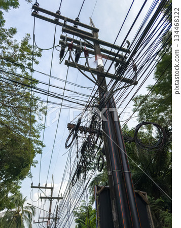 Asian poles with lots of wires at sunset, telecommunications in Thailand, chaos in the wires 134468122