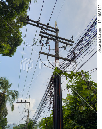 Asian poles with lots of wires at sunset, telecommunications in Thailand, chaos in the wires 134468123
