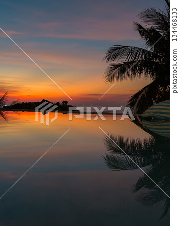 View from luxury villa at dusk, pool lighting, sun loungers for sunbathing, umbrellas from the sun, pillows for swimming in the pool, palm tree on background View from luxury villa at dusk, pool lighting, sun loungers for sunbathing, umbrellas from the sun, pillows for swimming in the pool, palm tree on background 134468133