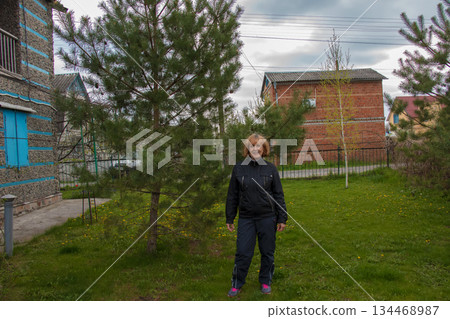 Portrait of happy elderly beautiful woman near beautiful fir trees in her garden. 134468987