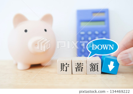 一張小豬存錢筒的圖片，上面有一個向下的箭頭，表示存款正在減少。 134469222