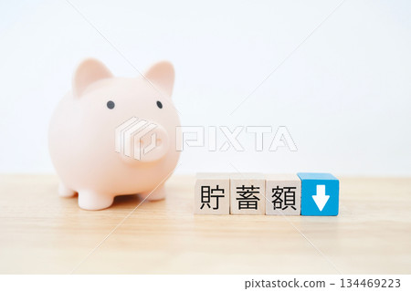 一張小豬存錢筒的圖片,上面有一個向下的箭頭,表示存款正在減少。 一張小豬存錢筒的圖片,上面有一個向下的箭頭,表示存款正在減少。 134469223