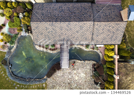 Aerial view of beautifully landscaped recreation house cottage complex with pond in ecological area on bright sunny day. Modern architecture, riches and luxury concept. 134469526