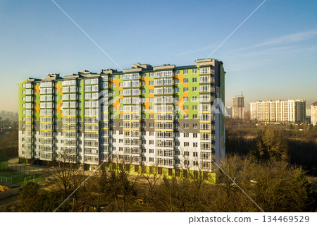 Aerial view of a tall residential apartment building with many windows and balconies. Aerial view of a tall residential apartment building with many windows and balconies. 134469529