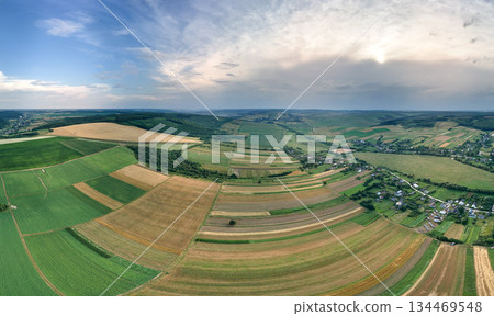 Aerial landscape view of green and yellow cultivated agricultural fields with growing crops on bright summer day Aerial landscape view of green and yellow cultivated agricultural fields with growing crops on bright summer day 134469548