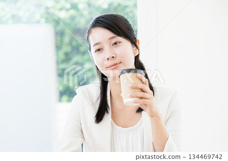 Woman drinking coffee while working 134469742
