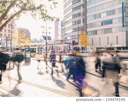 A long exposure of a sunny urban scene with pedestrians walking by 134470149