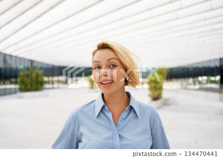 Confident businesswoman smiling near modern office Confident businesswoman smiling near modern office 134470441