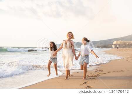 Cheerful mother with daughters running together Cheerful mother with daughters running together 134470442