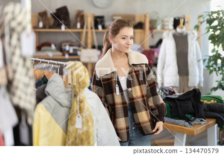 Young woman trying on plaid jacket in store Young woman trying on plaid jacket in store 134470579