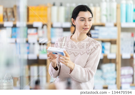 woman holds a package of ointment in her hands at a pharmacy woman holds a package of ointment in her hands at a pharmacy 134470594