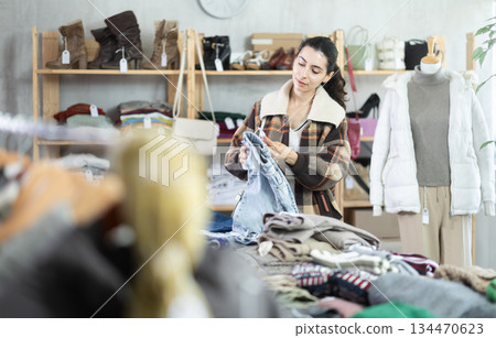 Female shopper chooses a jeans trousers in clothing store Female shopper chooses a jeans trousers in clothing store 134470623