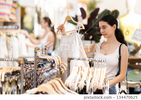 Girl customer chooses singlet blouse in branded store Girl customer chooses singlet blouse in branded store 134470625