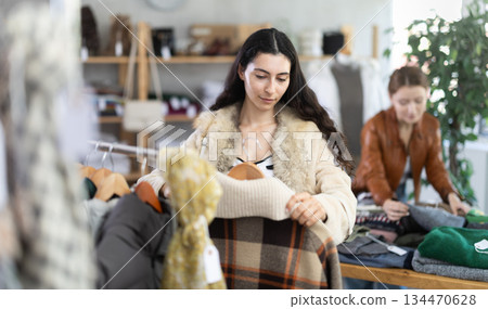 Young woman chooses plaid jacket in clothing store 134470628