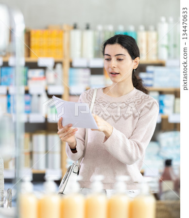 Woman with medical prescription in hand looking for medicine in pharmacy Woman with medical prescription in hand looking for medicine in pharmacy 134470633