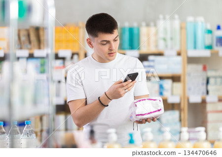 Young man in pharmacy scans QR code on sanitary pads 134470646