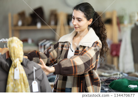 Armenian girl near showcase examine goods, buying something autumn outwear. Armenian girl near showcase examine goods, buying something autumn outwear. 134470677