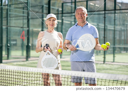 Young happy woman standing in padel court getting ready for match Young happy woman standing in padel court getting ready for match 134470679
