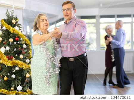 Middle-aged man and elderly woman dancing contemporary discofox in couple in New Year atmosphere Middle-aged man and elderly woman dancing contemporary discofox in couple in New Year atmosphere 134470681