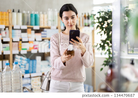 Woman scans the barcode of medicated syrup for cough Woman scans the barcode of medicated syrup for cough 134470687